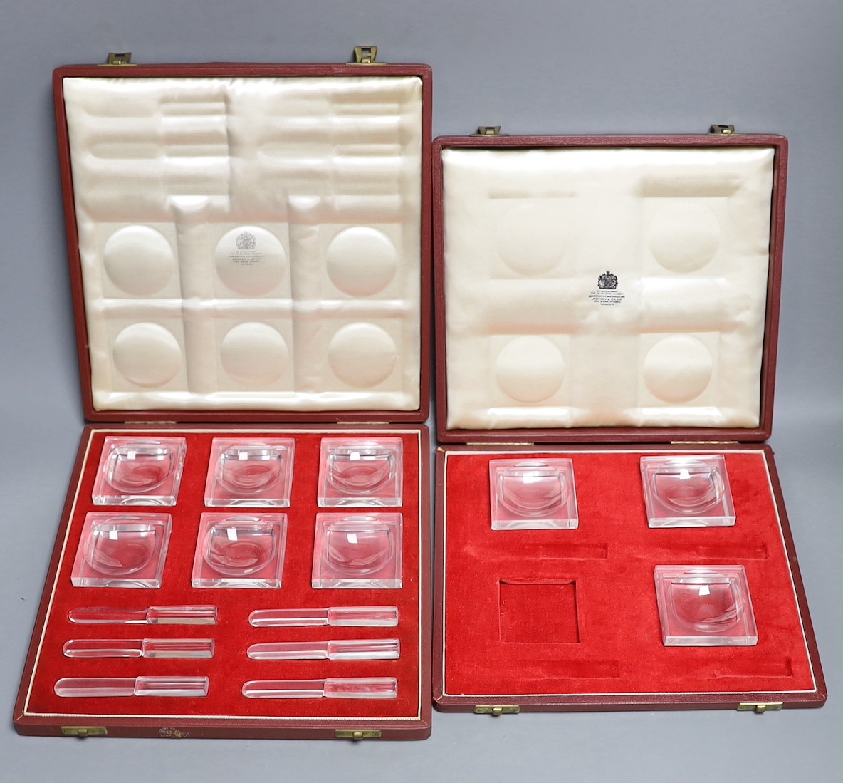 In incomplete set of Baccarat butter dishes together with a complete set of Baccarat butter dishes and knives, both in Asprey fitted cases